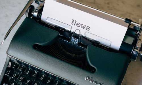 The word "News" typed on a paper inside of a green typewriter.