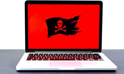 Laptop with red screen and black pirate flag on it.