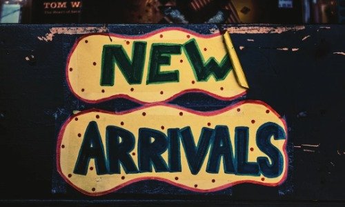 A blakc sign with yellow word ballons, inside the ballons are the words "New Arrivals"